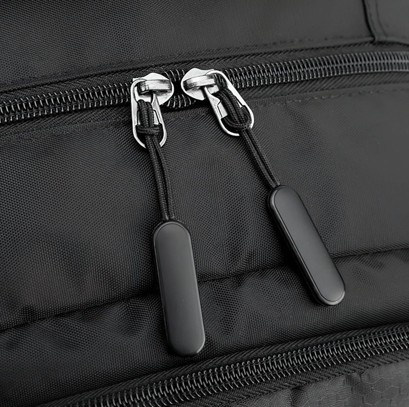 Close-up of black sports backpack zipper detail, showcasing dual metal pulls for secure closure.